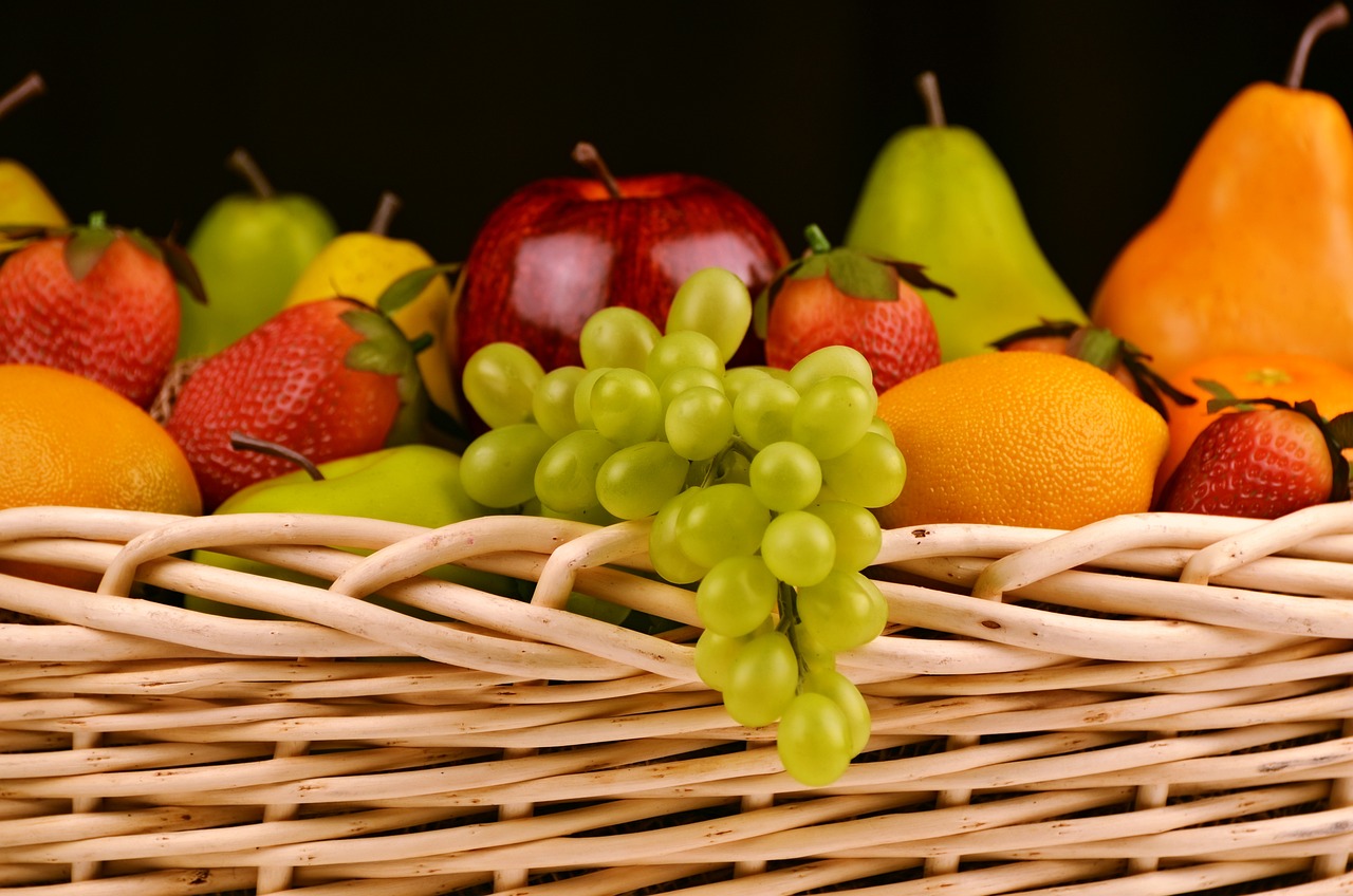 cesto de fruta con uvas colgando en un lateral